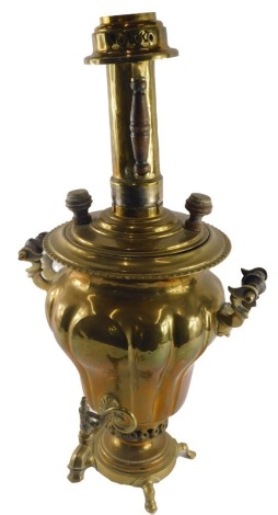 A late 19th/early 20thC continental brass samovar, with turned wooden handles and paw shaped feet, 62cm high.