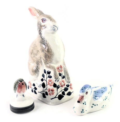 Three Rye pottery figures, comprising a Rye pottery rabbit on floral base dated 2004, 22cm high, a robin on perch signed RW, 8cm high, and a seated duck in blue and green spotted detail dated 2004, 13cm wide. (3)