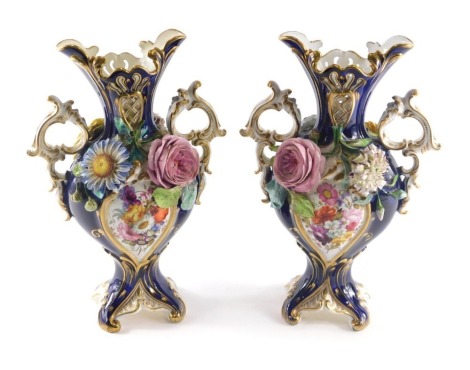 A pair of 19thC English porcelain two handled vases, each with pierced decoration, hand painted with flowers, and with encrusted flowers and leaves, on a cobalt blue ground picked out in gilt, on a shaped square base, 32cm high.