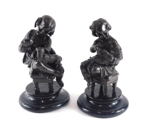 A pair of bronzed spelter figures, each modelled in the form of a putto with dogs, on ebonised base, 30cm high.