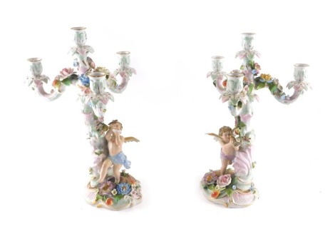 A pair of late 19th/early 20thC German flower encrusted figural four branch candelabra, each decorated with flowers and with a putto, 38cm high.