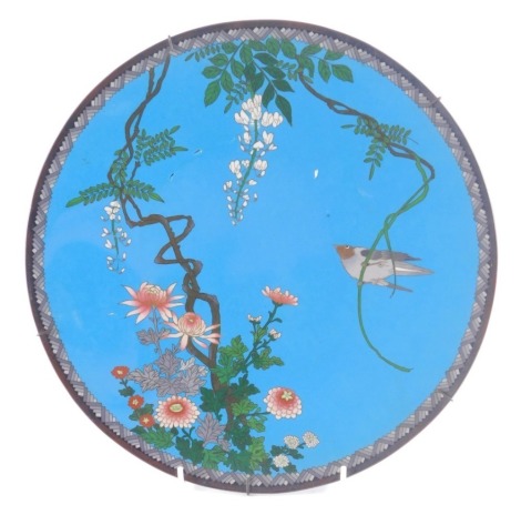 A late 19th/early 20thC Japanese cloisonne charger, decorated with a bird, flowers, etc., on a blue ground with geometric border, 30cm diameter.