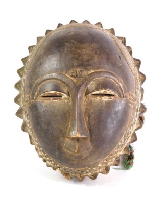 An African tribal Baule sun mask, with carved borders, Cote D'Ivoire, 30cm high.