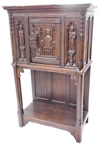 A 19thC oak carved Gothic cabinet, the rectangular top above a carved and frieze door, with two figure caryatids, and a lower shelf, on stiles, 142cm high, 85cm wide, 44cm deep.