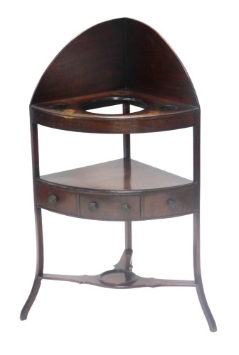 A George III mahogany corner washstand, with raised top above thee recesses the under tier with a central drawer flanked to two false drawer, on splayed legs, 111cm high, 60cm wide.