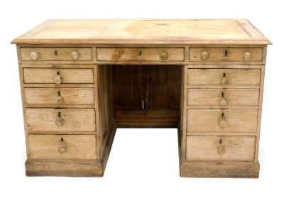 A late Victorian pine pedestal desk, top with moulded edge, above an arrangement of eleven drawers, each with turned wood handles, on a plinth, 81cm high, 135cm wide, 74cm deep. (AF)