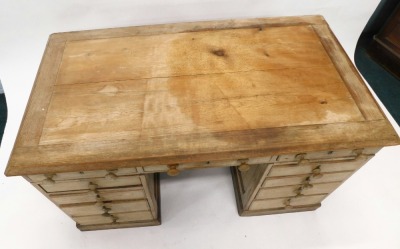 A late Victorian pine pedestal desk, top with moulded edge, above an arrangement of eleven drawers, each with turned wood handles, on a plinth, 81cm high, 135cm wide, 74cm deep. (AF) - 2