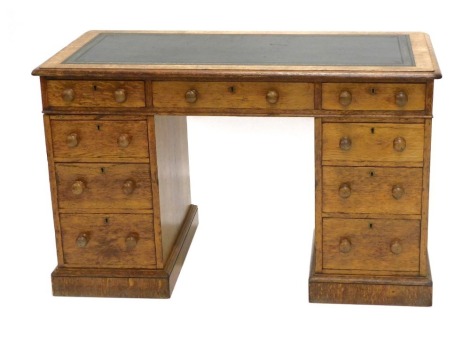 A late Victorian oak pedestal desk, the rectangular top inset with green leather and a moulded edge above an arrangement of nine drawers, on a plinth, 75cm high, 122cm wide, 61cm deep.