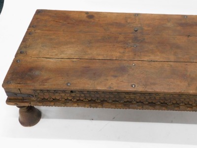 An Eastern hardwood table, the rectangular planked top with iron bolts or nails, above a carved frieze, on bell shaped legs, possibly Indian and constructed from old timber, 40cm high, 51cm wide, 78cm deep. - 2