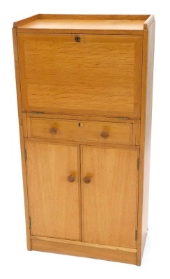 A light oak escritoire or bureau, in Heals style, with a raised gallery, enclosing a fitted interior with brown leatherette insert, with frieze drawer and two doors, each with turned handles, on a plinth, unmarked, 117cm high, 59cm wide.