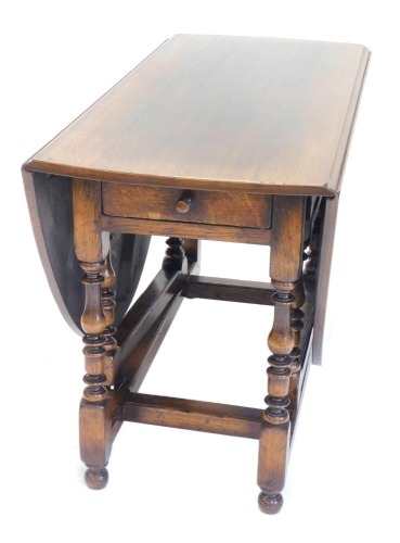 An oak drop leaf table, the oval top on part turned supports with bun feet, 120cm wide.