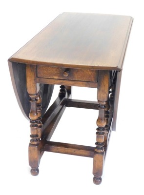 An oak drop leaf table, the oval top on part turned supports with bun feet, 120cm wide.