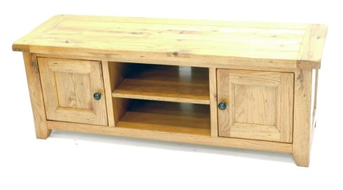 An oak television or media unit, the rectangular planked top above a recess flanked by two panelled doors, on styles, 50cm high, 134cm wide.