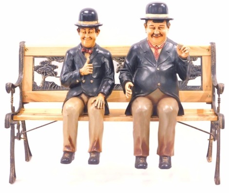 Two painted composition figures of Laurel and Hardy, 63cm high, and a stained pine bench, with Noah's ark back.