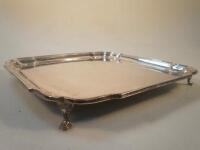 A George V rectangular silver salver with pie crust edge on four hoof feet by Barkers Brothers Ltd