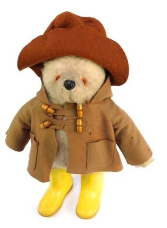 A Paddington Teddy Bear, in standing position, wearing brown felt hat, duffel coat and yellow Wellington boots, 49cm high.