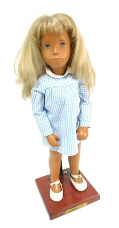 A 1970s Sasha doll, full height, blonde figure with blue eyes in blue chequered dress, on stand, stamped Alexandra, 41cm high.