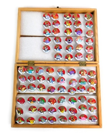 A group of Pokemon 2000 collectors pin badges, each depicting a different character, contained in an oak case. (quantity)