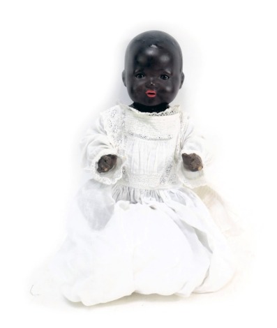 An Armand Marseille bisque headed doll, with roll eyes, black face and body, numbered 351372, in linen gown, 42cm high.