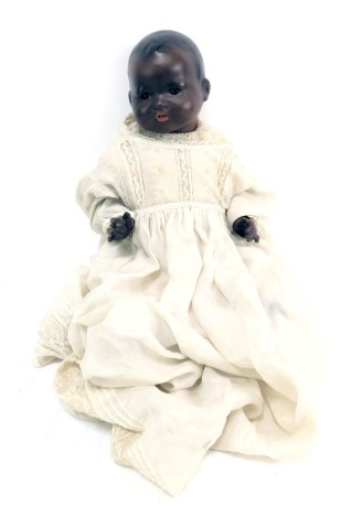 An Armand Marseille bisque headed doll, blacked face and body with brown roll eyes and teeth, numbered 351-4K, 42cm long.