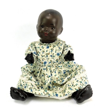 A bisque headed doll, with blackened face and roll brown eyes with teeth, with articulated limbs stamped HW 1, with floral dress, 31cm high.