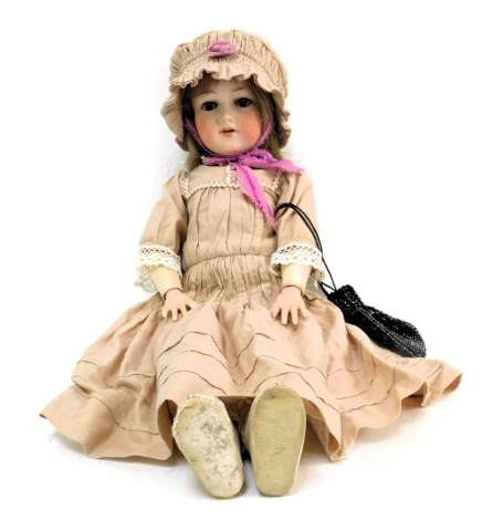 An Armand Marseille bisque headed German doll, with roll brown eyes and teeth, on articulated limbed body, stamped 390A.5.M, in pink dress with booties, 53cm high.