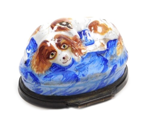 A late 18thC Bilston enamel bonbonniere, of oval form, moulded with a recumbent spaniel on a blue ground, the lid painted with a spray of flowers, 52mm wide. (AF)