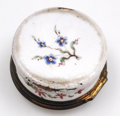 A late 18thC Continental enamel snuff box, possibly French, of cylindrical form, decorated to the lid with a man playing bagpipes, and a seated hound, the box with floral sprays, all on a white ground, 55mm diameter. (AF) - 3