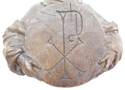 A late 17thC Continental carved wooden bust of a saint, half length, holding a roundel with a sacred monogram, 31cm high. - 2