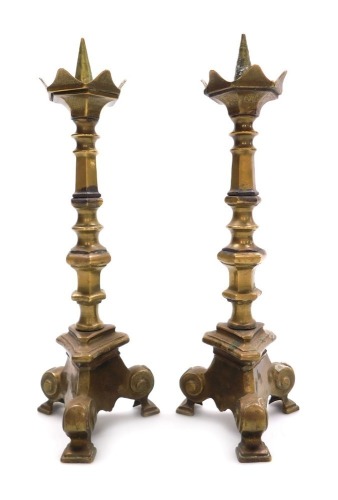 A pair of late 19thC Continental Gothic style brass altar candlesticks, raised on three scroll feet, 27cm high.