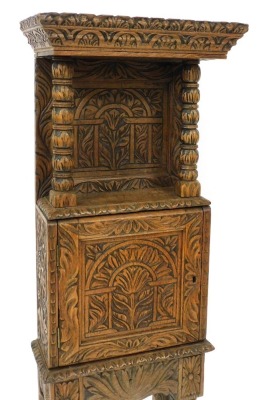 A late 19thC Jacobean style oak cupboard, of narrow proportions, with all over tree and foliate carving, the outswept pediment above a panelled back, raised on turned columns, over a cupboard enclosing a vacant interior, raised on a table base with cup an - 2