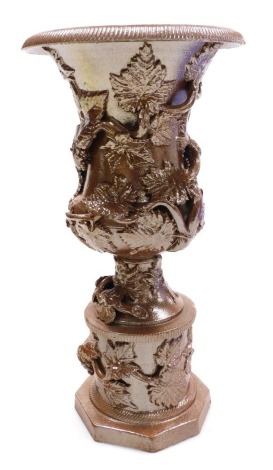 A mid 19thC Continental brown glazed stoneware vase, of baluster form, moulded with vines, raised on a plinth base, 27cm high.