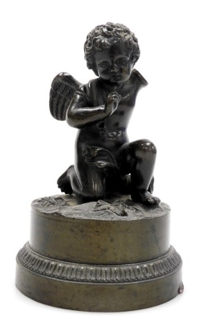 An early 19thC bronze figure of a kneeling cherub beside an arrow quiver, raised on a circular base, 11cm high. (AF)