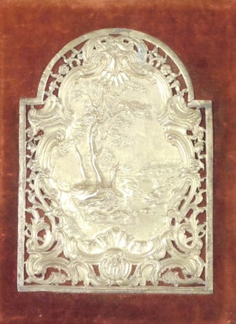 A 19thC Continental silvered bronze plaque of heart form, embossed and pierced with trees, flowers and rococo scrolls, against a red velvet back, framed, plaque 15cm x 11cm.