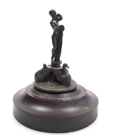 An early 19thC bronze figure or figural lid, modelled as a classical maiden atop a plinth flanked by three swans, on a circular base embossed with flowers, 11.5cm high.