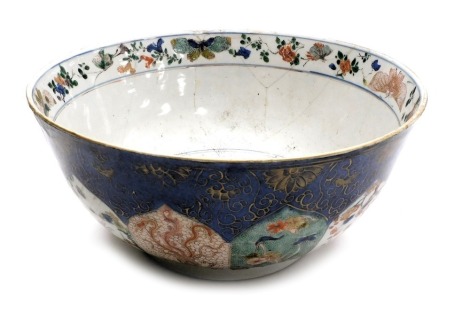 A Qing Dynasty early 19thC Chinese porcelain blue ground bowl, decorated externally with panels of birds, a phoenix, lion dog, and Buddhist emblems, internally with flowers and a band of butterflies and flowers, 29.5cm wide. (AF)