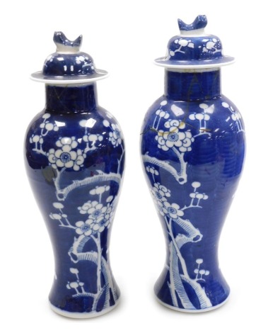 Two Qing Dynasty 19thC blue and white Chinese porcelain vases and cover, of baluster form, decorated with prunus blossom against a cracked ice ground, 33.5cm and 32cm high respectively. (AF)