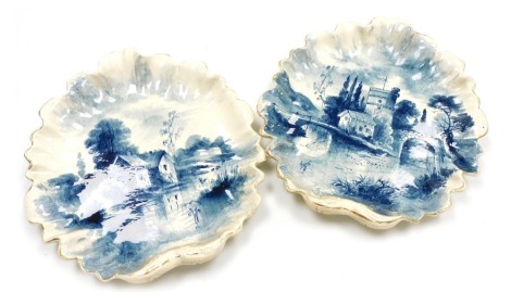 A pair of Dutch late 19thC pottery wall plates, modelled as scallop shells, painted in blue and white with river landscapes, monogrammed, signed indistinctly and titled verso, 39cm high.