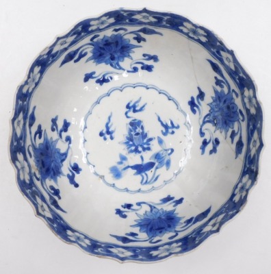 A Kangxi early 18thC blue and white Chinese porcelain bowl, of fluted form, decorated with flowers and Buddhist emblems within cloud borders, internally with flowers, impressed Manifest Happy mark, 19cm wide. (AF) - 2