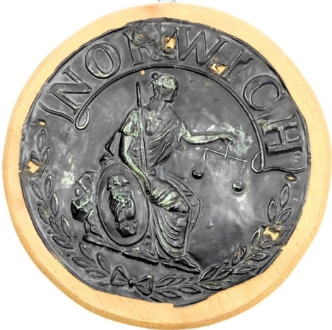 An early 19thC Norwich copper fire insurance mark depicting a seated figure of Justice, 19cm diam.