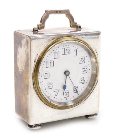 A George V silver cased travel clock, the circular white enamel dial bearing Arabic numerals, clockwork movement, the case of square form, with swing carrying handle, raised on bun feet, Hasset & Harper Ltd, Birmingham 1920, 4.5cm wide.