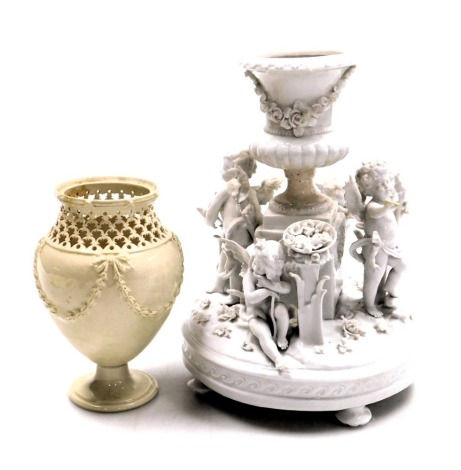 A late 18thC Leeds creamware pottery vase, with a reticulated neck, the body moulded with harebell swags, 15.5cm high, together with a 19thC Crown Naples white glazed porcelain centrepiece with a central floral encrusted vase on a plinth, flanked by stand