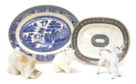 Three Lomonosov porcelain figures of animals, comprising a recumbent elephant, polar bear, and a donkey, together with a Swinnertons Old Willow pattern meat platter, and a Royal Doulton pottery tureen stand. (5)