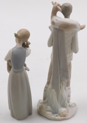 A Lladro bisque porcelain figure of a girl, modelled standing holding a lamb in her arms, 21cm high, and a further figure of a boy, with a goat around his shoulders, 27cm high. (2) - 2