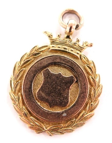 A 9ct yellow and rose gold pendant medallion, with a central circle and shield, within a laurel wreath border, with crown surmount, 11.1g.