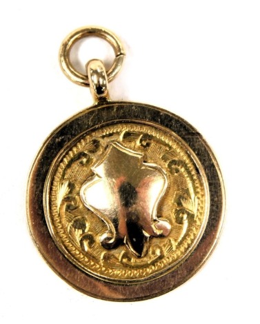 A 9ct gold circular medallion pendant, with engraved decoration and central vacant shield reserve, 4.9g.