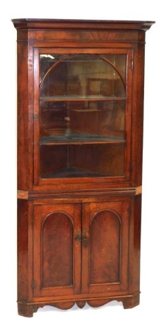 A Victorian mahogany corner display cabinet, the outswept pediment over an arched glazed door enclosing two shelves, above a pair of cupboard doors raised on bracket feet, 206.5cm high, 100cm wide, 56cm deep.