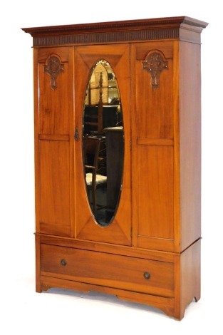 An Edwardian mahogany wardrobe, with single oval mirrored door, carved panels flanking, with single drawer below, raised on bracket feet, 197cm high, 130cm wide, 4cm deep.