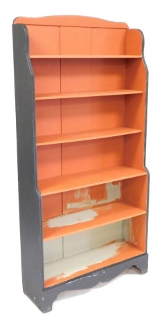 A red and black painted waterfall bookcase, of six shelves, raised on bracket feet, 174cm high, 84cm wide, 28cm deep.