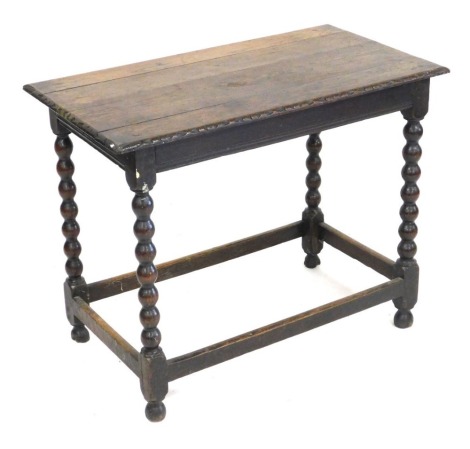 A 17thC oak occasional table, raised on bobbin turned legs, united by a box stretcher, 70cm high, 87cm wide, 48cm deep.